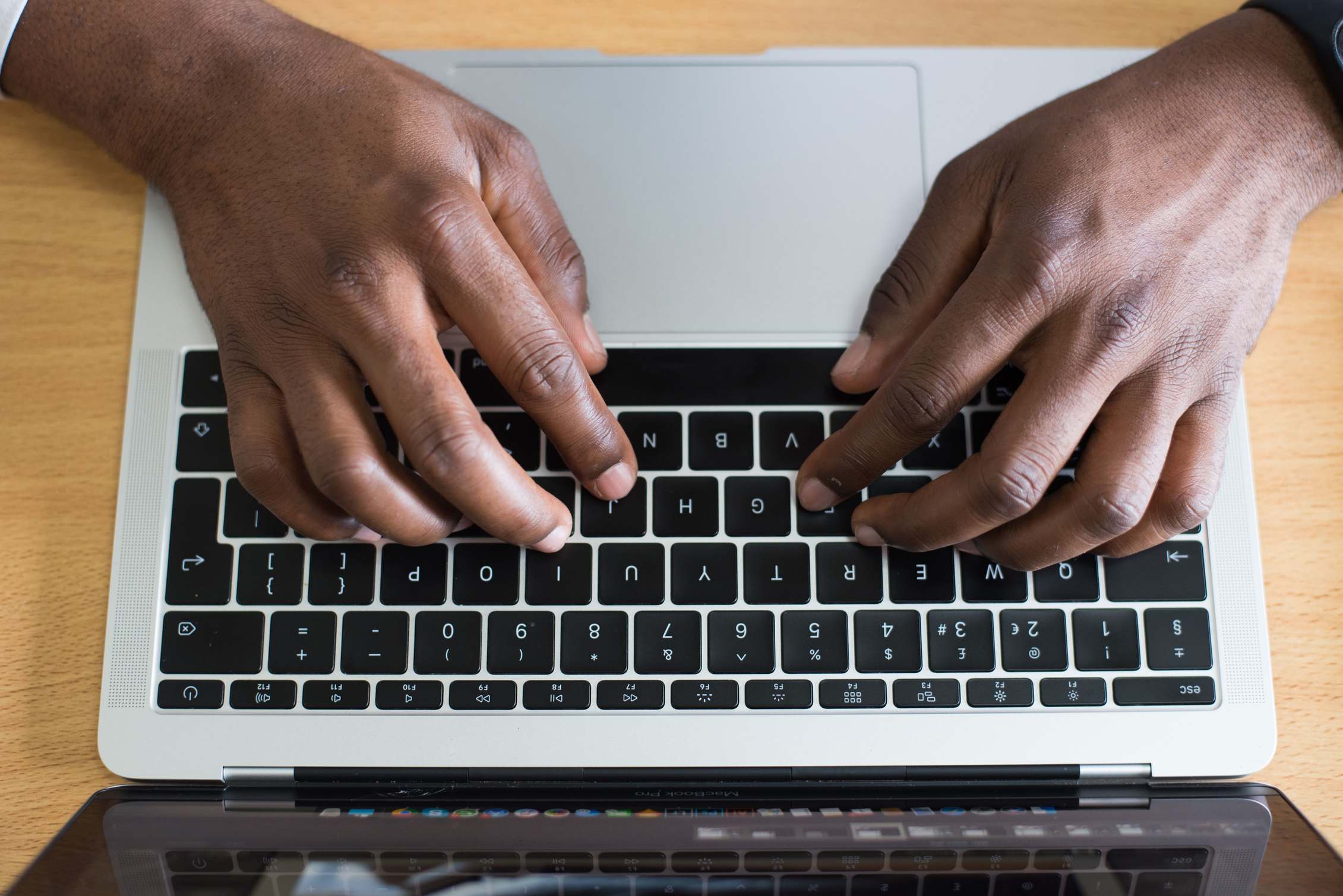 Hands working on a laptop at a desk during a coding session